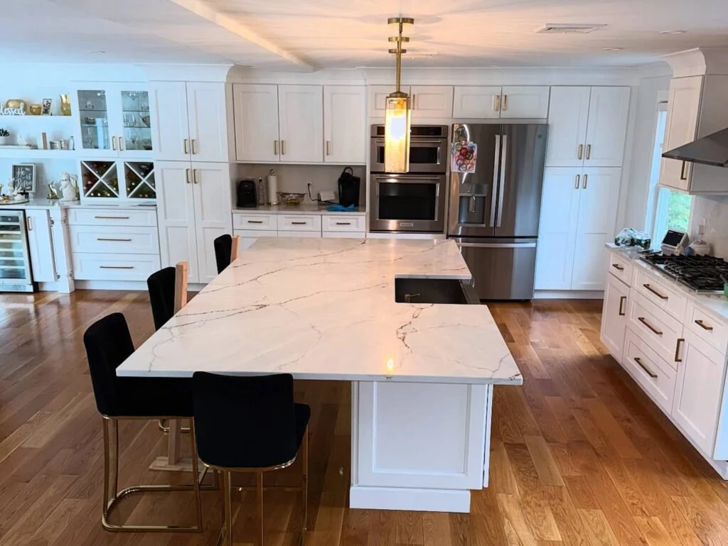 Completed white kitchen remodel with a waterfall island, custom storage, and wood flooring
